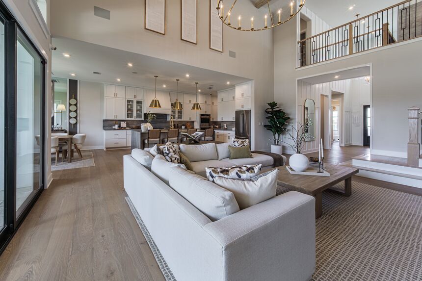 Two-story living room with white sofas, open to the kitchen and the upstairs landing