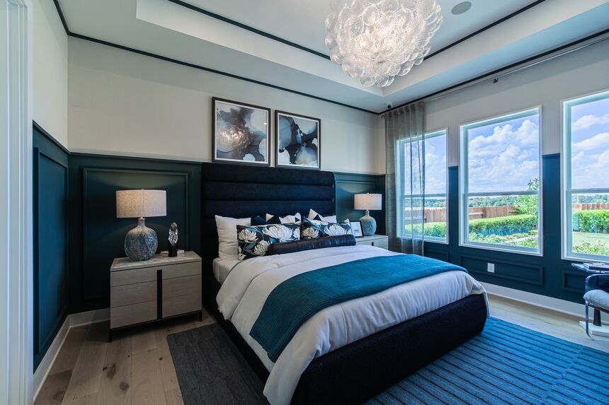 Primary bedroom with a navy accent wall and windows on two sides